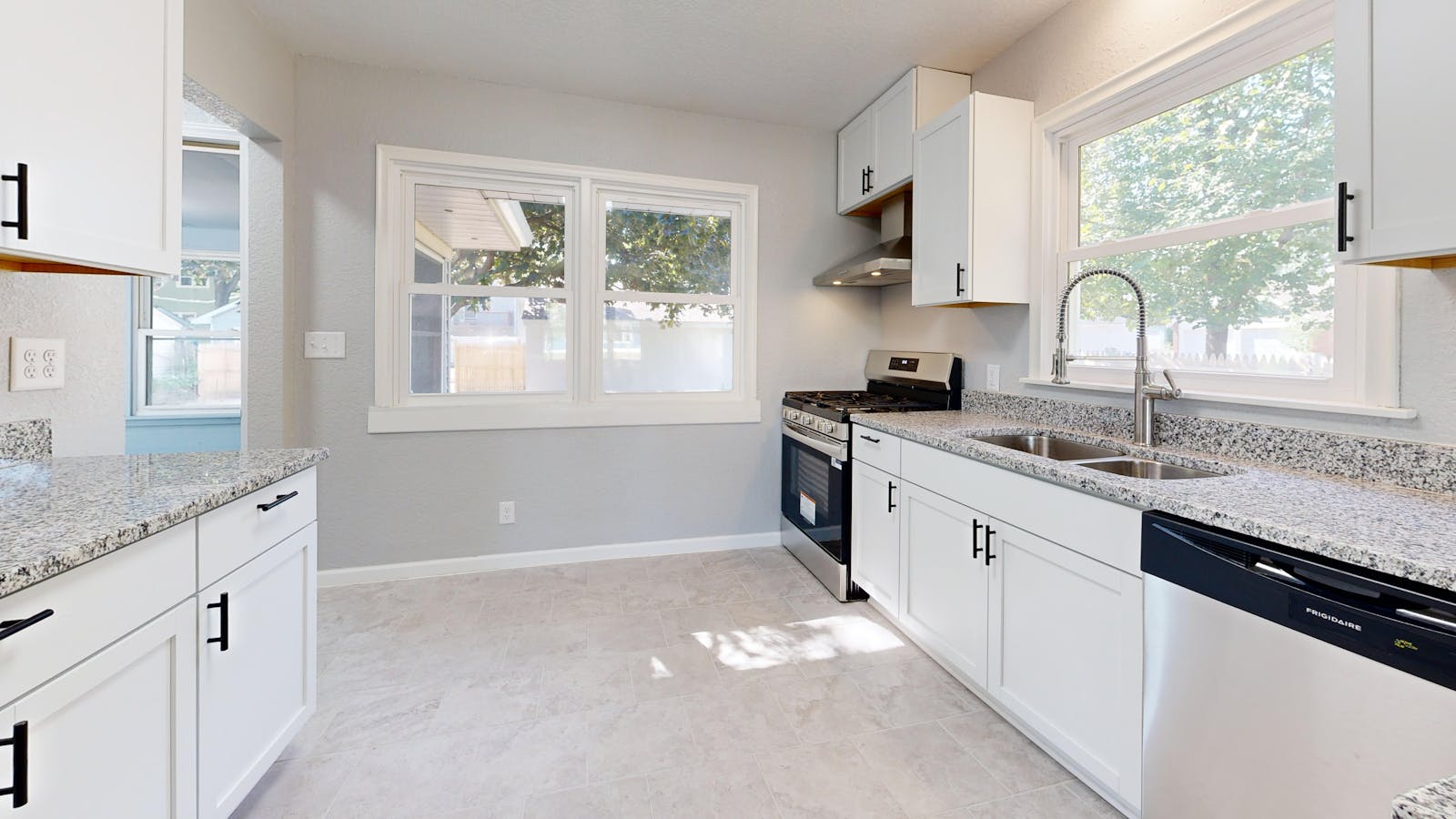 Sunlit modern kitchen with white cabinetry and granite countertops